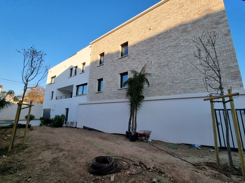 résidence avec façade neuve moitié moderne blanche, moitié pierre décorative